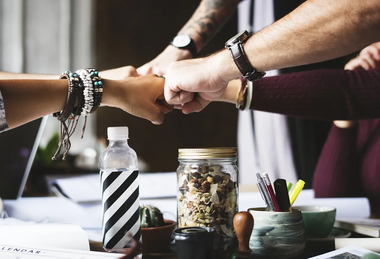 Team members bumping fists over a desk