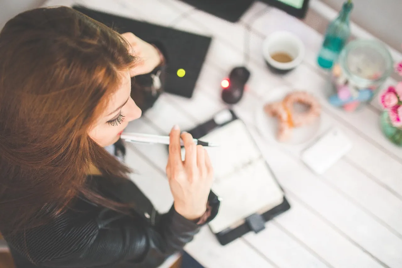 Woman holding a pen and planning with a notebook at a desk